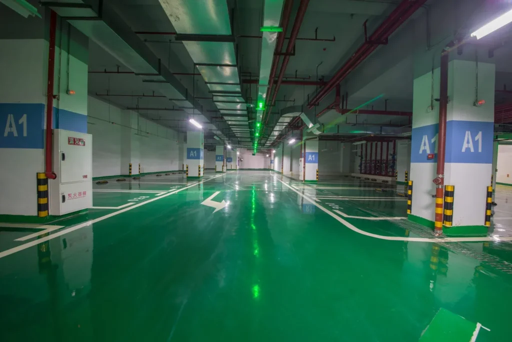 Green epoxy floor coating with white bay lines in a basement car park in Qatar